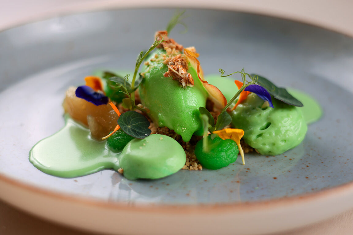 Farbenfrohes, grünes Dessert auf grauem Teller mit goldenem Rand, ergänzt durch Sorbet.