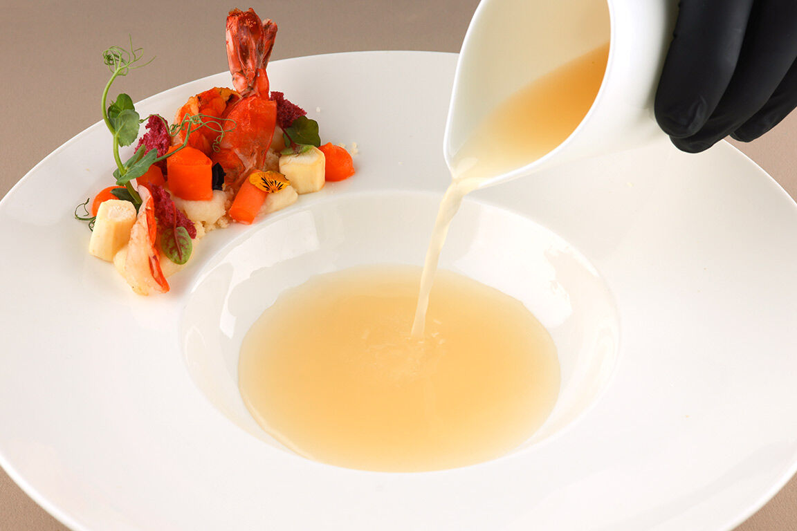 Pastinaken-Essenz wird angerichtet, dazu eine elegant platzierte Garnele.