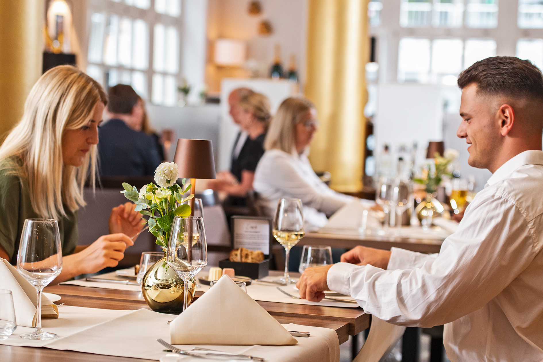 Paar genießt elegantes Dinner im Restaurant „Engels in der Burg“, stilvoll eingedeckt.
