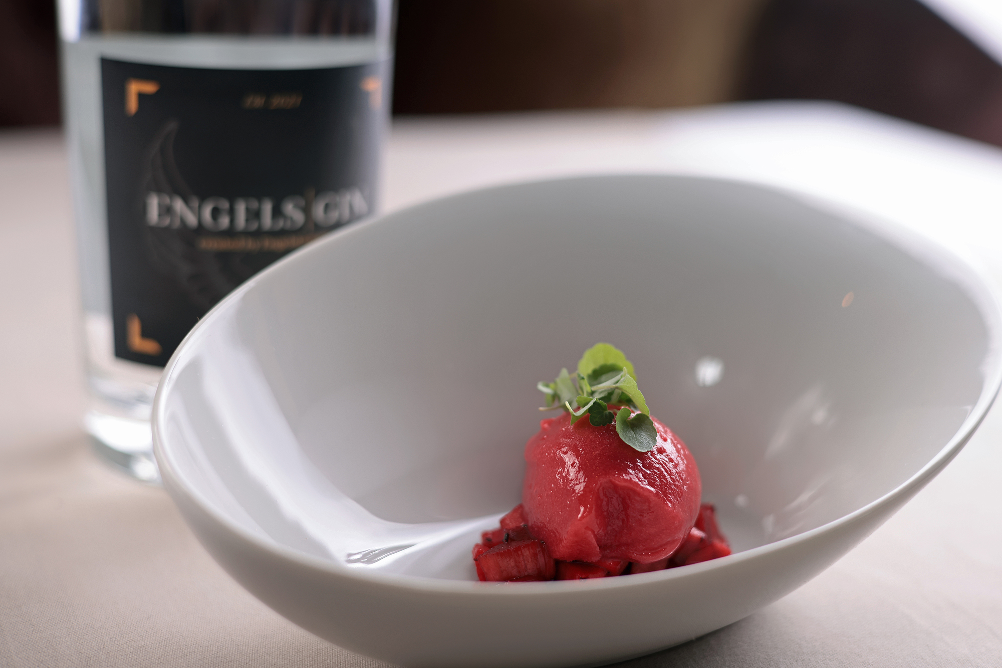 Knallrotes Sorbet vor Flasche Engels Gin, lebendiger Kontrast auf dem Teller.