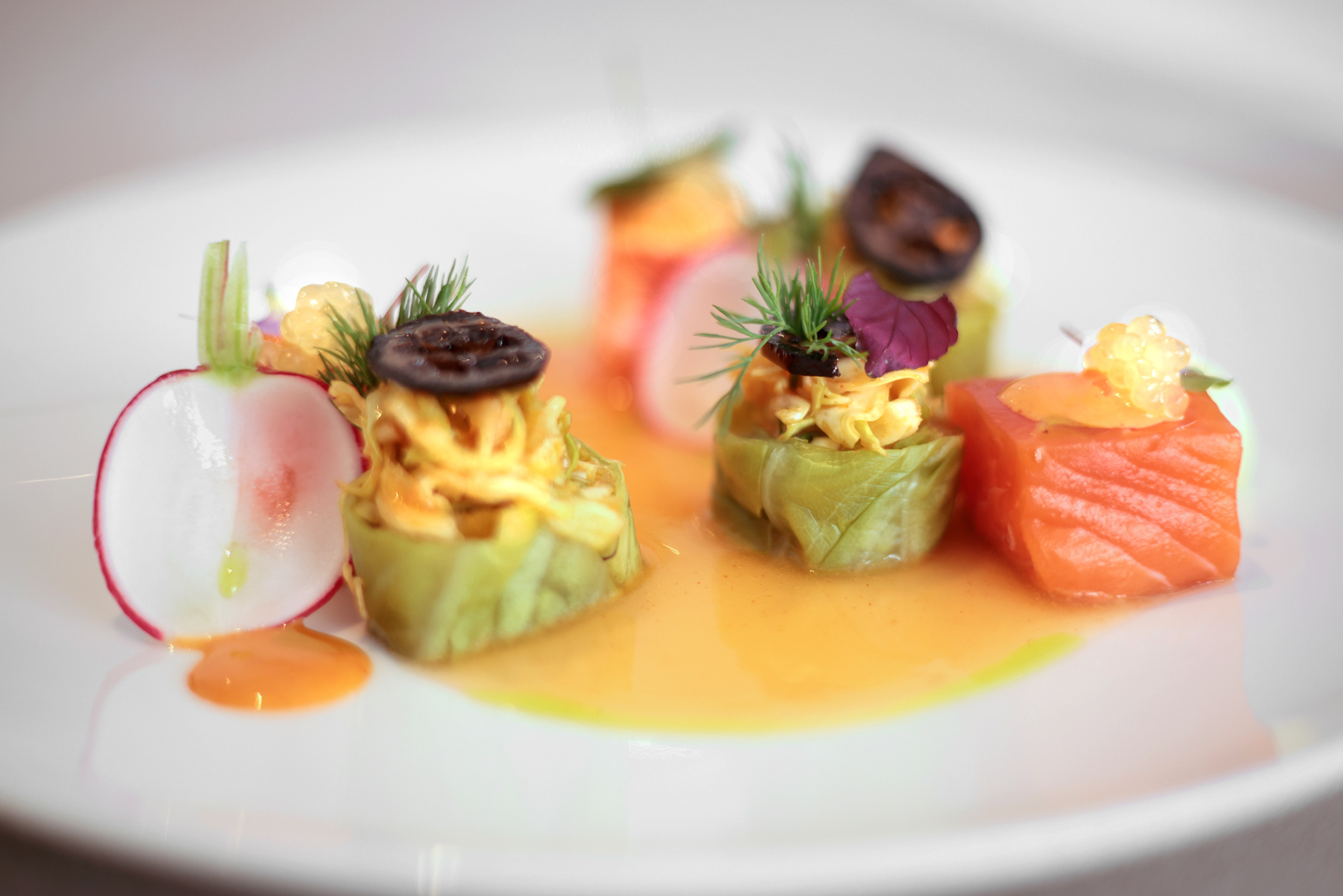 Ora King Lachswürfel auf Soßenspiegel, begleitet von frischer Melone, elegant arrangiert.