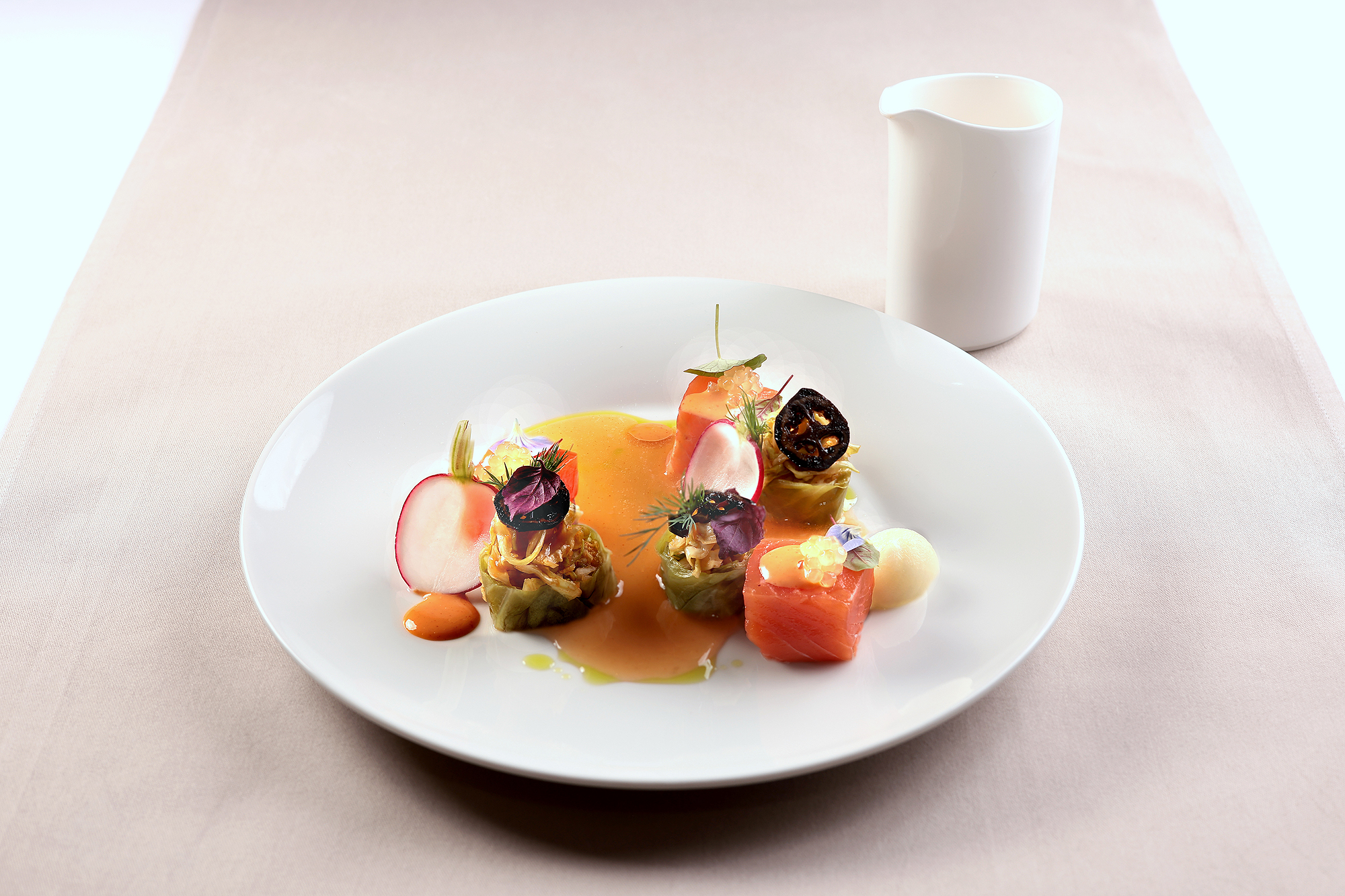Ora King Lachswürfel auf Soßenspiegel, begleitet von frischer Melone, farbenfroh arrangiert.